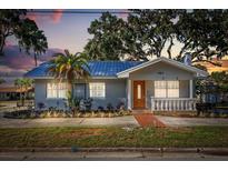 Charming single-story home featuring a blue metal roof, manicured landscaping, and a cozy front porch area at 465 W Lakeshore Dr, Clermont, FL 34711