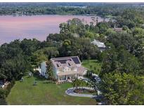 Stunning aerial view of a lakeside home with solar panels, mature trees, and a circular driveway at 5351 Carson St, St Cloud, FL 34771