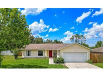Charming single-story home with a well-manicured lawn, attached garage, and a vibrant red front door at 10739 Lake Ralph Dr, Clermont, FL 34711