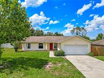 Charming single-story home featuring a bright red door, green lawn, and attached two-car garage at 10739 Lake Ralph Dr, Clermont, FL 34711