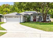 Charming single-story home with a well-manicured lawn, mature trees, and a driveway leading to a two-car garage at 10743 Fairhaven Way, Orlando, FL 32825