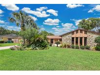 Landscaped front yard featuring a well-maintained lawn, stone facade, and lush tropical plants at 119 Rock Lake Rd, Longwood, FL 32750