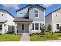 Charming two-story home boasts a beautiful blue exterior, well-manicured lawn, and welcoming front porch at 14111 Frasier St, Winter Garden, FL 34787