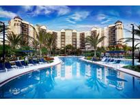 Stunning pool area with lounge chairs and umbrellas surrounded by tropical landscaping and the building's reflection at 14501 Grove Resort Ave # 2451, Winter Garden, FL 34787