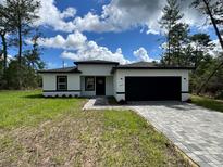 Charming single-story home with a black two-car garage and beautifully paved driveway at 16463 Sw 55Th Court Rd, Ocala, FL 34473