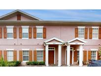 Charming townhome featuring a symmetrical facade, brown shutters, and private front entrances with white pillars at 2411 Caravelle Cir, Kissimmee, FL 34746