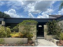 Charming home's entrance with a gated courtyard and lush landscaping under a partly cloudy sky at 2426 Windward Way, Winter Park, FL 32792