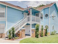 Charming blue condo with white staircase, American flag, and well-maintained landscaping at 2729 N Poinciana Blvd # 125, Kissimmee, FL 34746