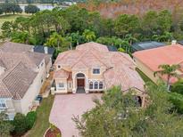Beautiful aerial view of a luxury house with a tile roof surrounded by lush landscaping and a lake in the background at 2828 Northampton Ave, Orlando, FL 32828