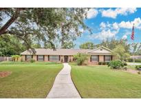 Charming single-story home features a well-manicured lawn and a welcoming front entrance with an American flag at 603 S Sweetwater Blvd, Longwood, FL 32779
