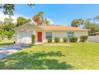 Charming single-story home with well-maintained lawn, red door, and attached garage at 620 Unabelle Ave, Holly Hill, FL 32117