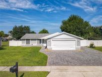 Charming single-story home with a manicured lawn, brick driveway, and a two-car garage at 7911 Murcott Cir, Orlando, FL 32835