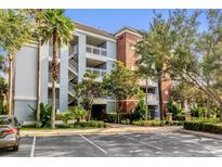 Exterior view of a three-story condominium building with manicured landscaping and ample parking at 1100 Sunset View Cir # 204, Reunion, FL 34747