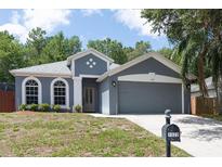Charming gray home featuring arched windows, a two-car garage, and manicured landscaping at 1322 Reagans Reserve Blvd, Apopka, FL 32712