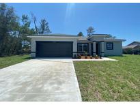 Charming single-story home with a dark grey garage door, fresh landscaping, and a well-manicured lawn at 182 Marion Oaks Mnr, Ocala, FL 34473
