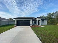 Beautiful single-story home boasts a modern design, dark accents, a two-car garage, and a well-manicured front yard at 2750 Sw 144Th Pl, Ocala, FL 34473