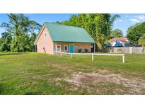 Charming tan home with vibrant blue door, green roof, and spacious front yard, offering a welcoming curb appeal at 287 Hilltop Dr, Longwood, FL 32750