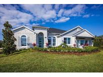 Single-story home featuring stone accents, arched entryway, landscaped front yard, and visible 'Sales Center' sign at 3126 Wolf Lake Ave, Apopka, FL 32712