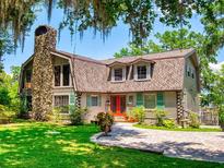 Charming exterior of home with a stone chimney, wood siding, and a well-manicured lawn at 3443 S Mellonville Ave, Sanford, FL 32773