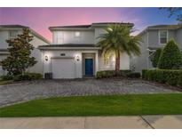 Beautiful two-story home with a blue front door, lush landscaping, and a brick driveway at 4740 Sleepy Hollow Dr, Kissimmee, FL 34746