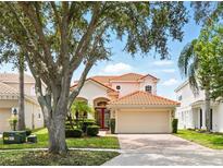 Charming home boasts a red tile roof, manicured lawn, and inviting red double-door entry at 8418 Via Bella Notte, Orlando, FL 32836