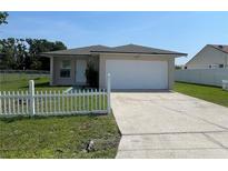 Charming single-story home featuring a white picket fence, green lawn, and attached two-car garage at 909 San Paulo Way, Kissimmee, FL 34758