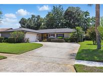 Charming single-story home featuring a well-manicured lawn and a spacious driveway leading to an attached two-car garage at 1017 Manchester Cir, Winter Park, FL 32792