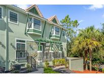 Charming townhome with green paint, stone accents, and a well-manicured landscape with palm trees at 14513 Damai Ln, Orlando, FL 32821