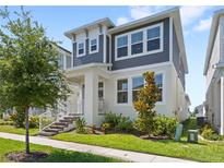 Charming two-story home with gray and white exterior, lush landscaping, and inviting front porch at 15444 Lebeau Loop, Winter Garden, FL 34787