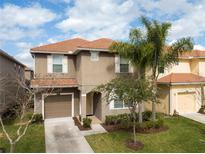 Charming two-story home with a tile roof, well-manicured lawn, and an attached one car garage at 2928 Buccaneer Palm Rd, Kissimmee, FL 34747