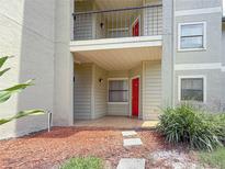Inviting condo entrance with a red door, stone walkway, and manicured landscaping at 3034 Parkway Blvd # 102, Kissimmee, FL 34747