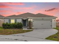 Charming single-story home with a two-car garage, landscaped yard and beautiful sunset sky at 3405 Yarian Dr, Haines City, FL 33844