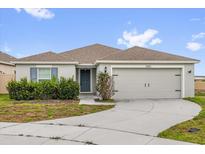 Charming single-story home featuring a two-car garage, landscaped yard, and neutral-toned facade at 3405 Yarian Dr, Haines City, FL 33844