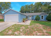 Charming one-story home with blue exterior, well-maintained landscaping, and a two car garage at 5032 Timber Ridge Trl, Ocoee, FL 34761
