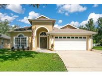 Inviting single-story home with well-manicured lawn, arched entryway and two-car garage at 608 Ashwell Ct, Debary, FL 32713