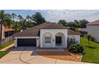 A bright, white single-story home with a two-car garage and charming arched entryway at 641 Lakescape Ct, Orlando, FL 32828