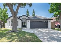 Charming single-story home with a two-car garage, classic white paint, and lovely yard with mature trees at 7646 Coconut Creek Ct, Orlando, FL 32822