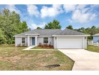 Charming single-story home with a well-maintained lawn, blue door, and attached two-car garage at 8 Water Trce, Ocala, FL 34472