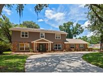 Charming two-story home features a brick and siding exterior, complemented by lush landscaping and a circular driveway at 120 Springwood Trl, Altamonte Springs, FL 32714