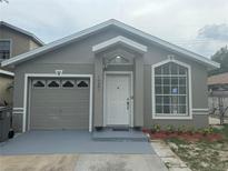Charming single-story home with a gray exterior, updated landscaping, and an attached one-car garage at 1241 Cleveland Ave, Apopka, FL 32703