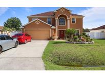 Charming two-story home featuring a well-manicured lawn and a welcoming front entrance with stone-edged garden at 314 Edgewood Ct, Kissimmee, FL 34759