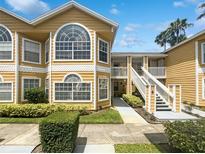 Charming yellow condominium with large windows, white trim, and manicured landscaping at 3142 Britannia Blvd # C, Kissimmee, FL 34747