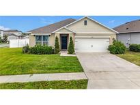 Charming single-story home with a two-car garage, beautifully landscaped lawn, and a welcoming dark blue front door at 3980 Gadwall Pl, Leesburg, FL 34748