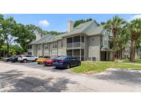 This is an exterior view of the condo building, showcasing its architecture, surrounding greenery, and parking area for residents at 6052 Westgate Dr # 204, Orlando, FL 32835