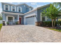 Beautiful two-story home with a charming porch and a brick driveway leading to the attached garage at 6333 Schoolhouse Pond Rd, Winter Garden, FL 34787