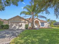 Charming single-story home featuring a well-manicured lawn, two car garage, and inviting entrance at 703 Sunridge Woods Blvd, Davenport, FL 33837