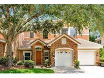 Charming two-story home featuring a stone facade, attached two-car garage, and a well-maintained lawn at 7521 Bay Port Rd # 12, Orlando, FL 32819