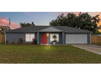 Charming single-story home featuring a well-maintained lawn, gray paint, and a red front door at 8 Lake Jackson Dr, Mascotte, FL 34753
