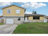 Two-story home with a stone foundation, yellow siding, and well-maintained lawn at 8652 Savory Dr, Orlando, FL 32825