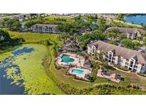 Aerial view of a community pool with cabanas and lounge chairs, surrounded by manicured lawns and trees at 8801 Latrec Ave # 8107, Orlando, FL 32819